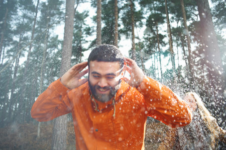 Young woman sprinkling boyfriend with water in forestの写真素材