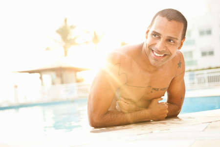 Mid adult man standing in sunlit hotel swimming pool, Rio De Janeiro, Brazilの写真素材