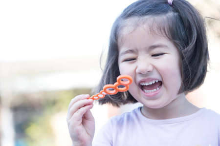 Young girl blowing bubbles, laughing, close-up