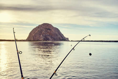 View of Morro Bay Rock between fishing rods, Morro Bay, California, USAの写真素材