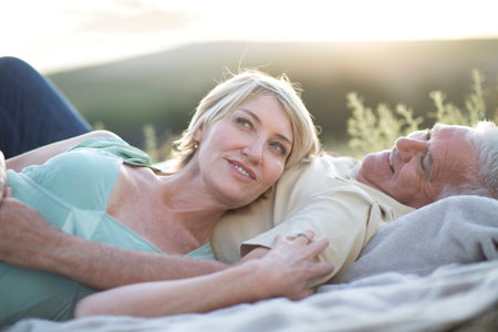 Mature couple lying together on blanket smilingの写真素材