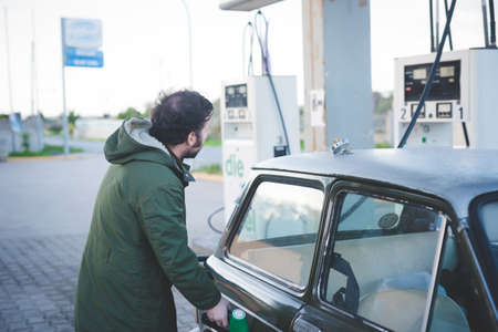 Man using fuel pump for vintage car in gas filling station