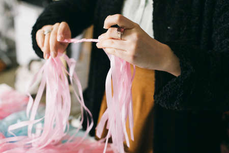 Close up of female textile designer twirling ribbons together in design studioの写真素材