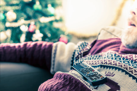 Man wearing sweater asleep with remote control on chestの写真素材