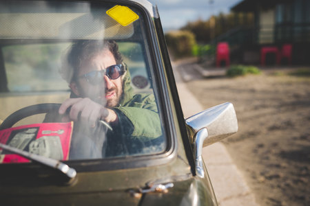 Man in parked vintage car looking through wing mirrorの写真素材