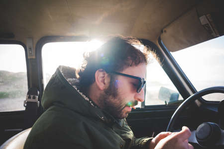 Man in car at beach rolling a cigaretteの写真素材