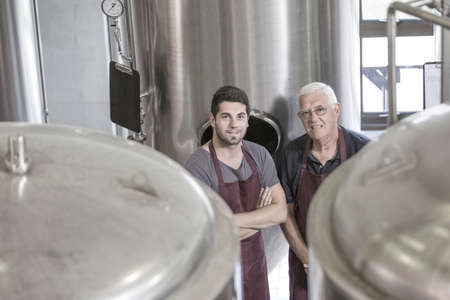 Brewers in brewery next to stainless steel tanks