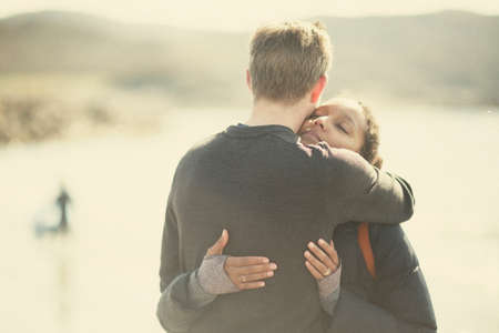 Mid adult couple hugging in sunlightの写真素材