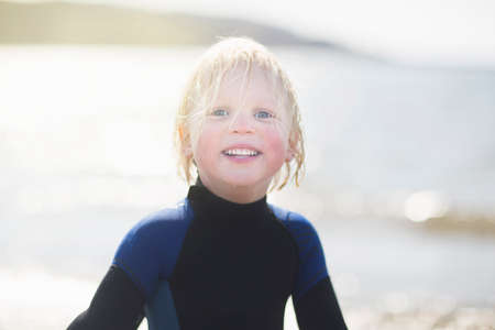 Boy with wet hair wearing wetsuit, portraitの写真素材