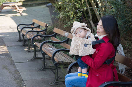 Mother sitting on bench with baby boyの写真素材