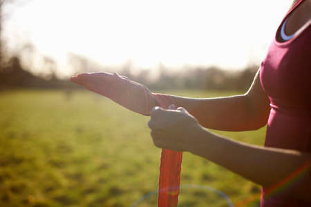 Cropped view of mature female boxer bandaging hands in field