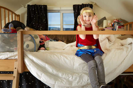 Portrait of young girl, sitting on bed, wearing fancy dress costumeの写真素材