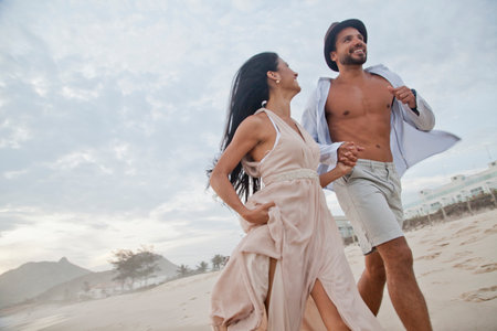 Mid adult couple running along beach, hand in hand, low angle viewの写真素材