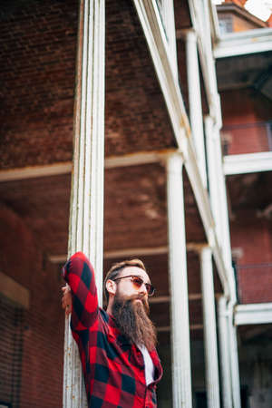 Man with beard leaning against a pillar
