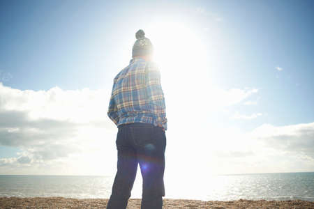 Mature man looking out to sea from beachの写真素材