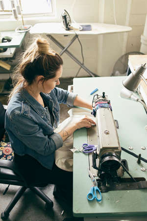 Female seamstress using sewing machine in fashion studioの写真素材