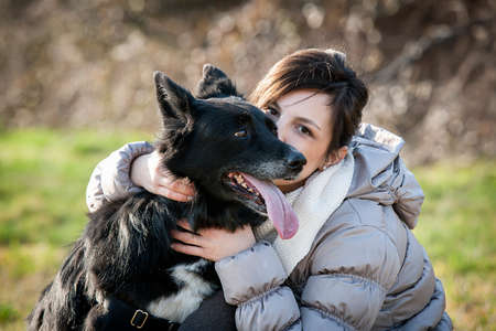 Portrait of mid adult woman kissing her dog in fieldの写真素材