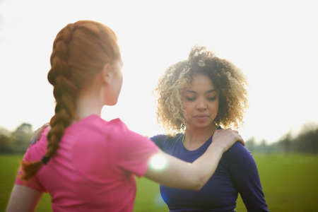 Two women exercising and stretching in the parkの写真素材