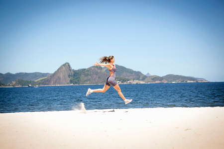Young woman jumping on beach, Rio de Janeiro, Brazilの写真素材