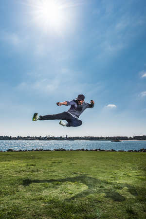 Fit mid adult man poised jumping mid air at coastの写真素材