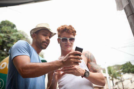 Two male friends looking at smartphone, low angle view