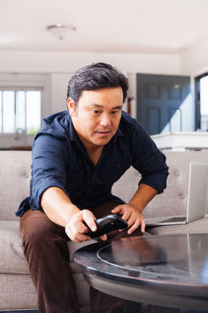 Mature man on sofa reaching for remote controlの写真素材