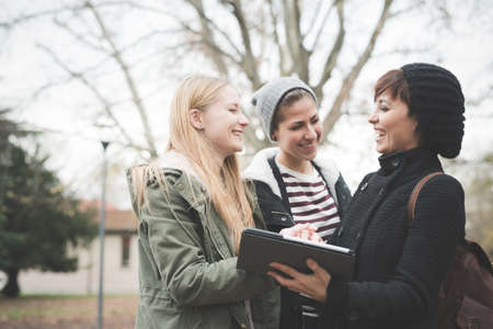 Three sisters using digital tablet in parkの写真素材