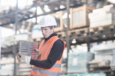 Young male warehouse worker steel product in warehouseの写真素材