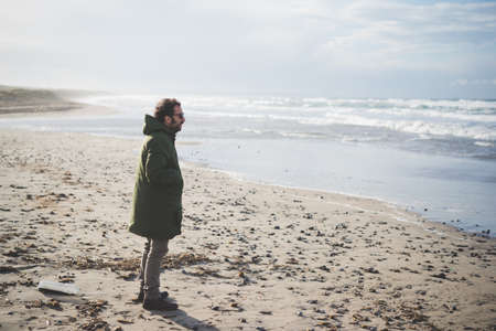 Mid adult man looking out at sea on windy beach, Sorso, Sassari, Sardinia, Italyの写真素材