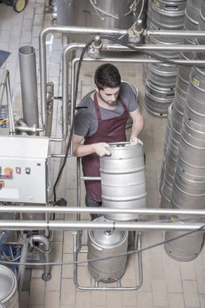 Brewer moving kegs in brewery