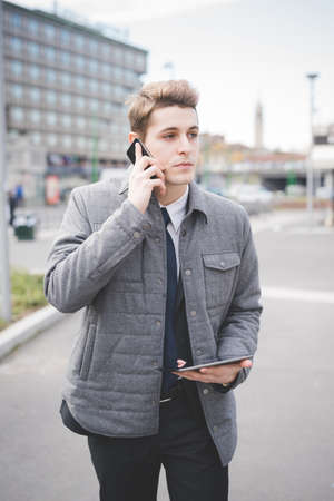 Portrait of young businessman using digital tablet and mobile phone.