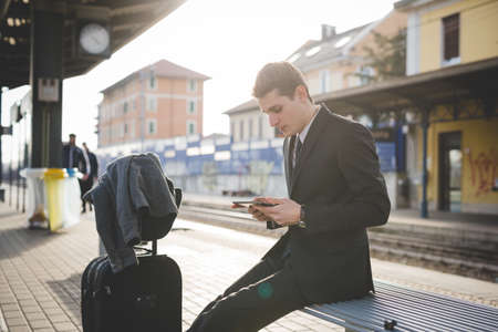 Portrait of young businessman commuter using digital tablet at train station.の写真素材