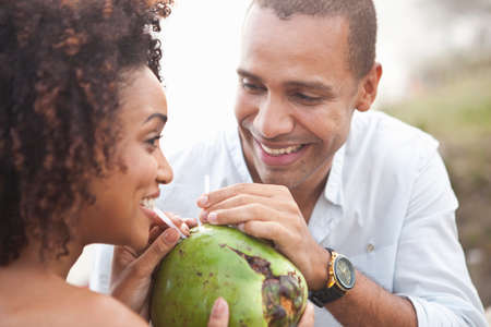 Close up of couple sharing coconut milk at beach, Rio De Janeiro, Brazilの写真素材