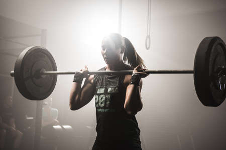 Young woman lifting barbellの写真素材