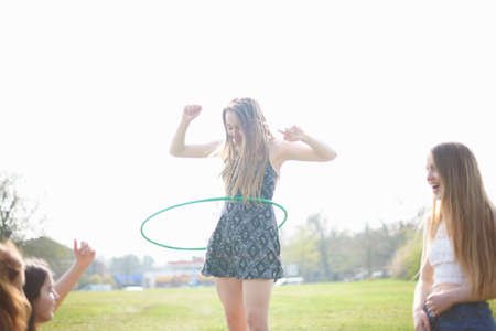 Teenage girl hoola hooping for friends in parkの写真素材