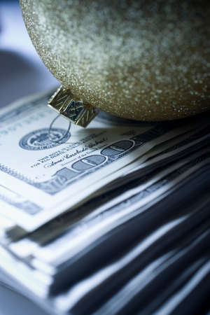 Sparkly christmas bauble on top of pile of 100 dollar billsの写真素材