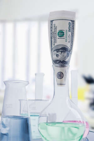 One hundred dollar bill in flat bottomed glass chemistry flaskの写真素材