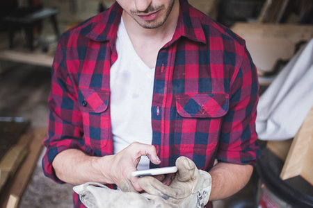 Cropped view of young mans hands wearing protective gloves using smartphoneの写真素材