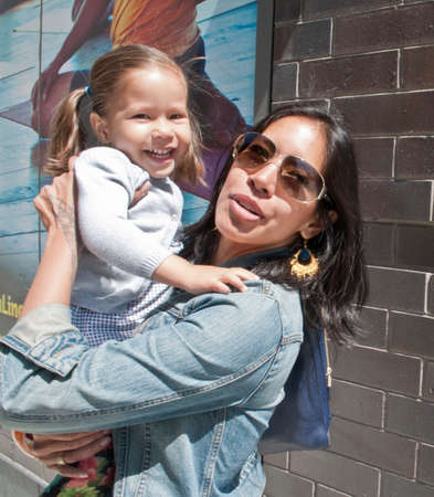 Portrait of mother carrying daughter in city