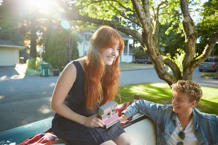 Young couple with vintage convertible using instant cameraの写真素材