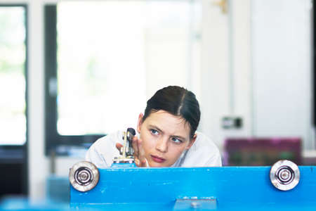Head and shoulders of young woman operating machineの写真素材