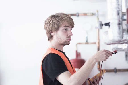 Side view of young man wearing high visibility vest testing heating system