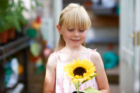 Portrait of girl holding sunflower in greenhouseの写真素材