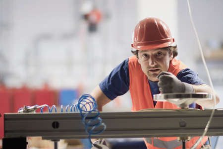 Mid adult man wearing hard hat looking at camera, operating machine