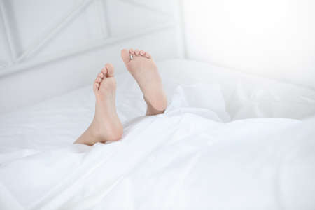 Feet sticking out of bedの写真素材