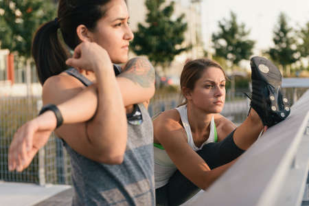 Two friends warming up to exercise together outdoors