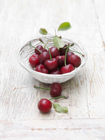 Cherries in wicker basket on whitewashed wooden table