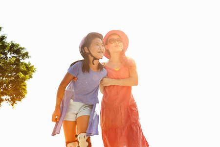 Woman with arm around rollerblading daughter in sunlight