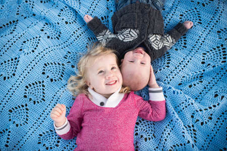 Overhead portrait of girl on blue picnic blanket with baby brotherの写真素材