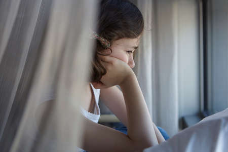 Sullen girl reclining on bed resting on elbow